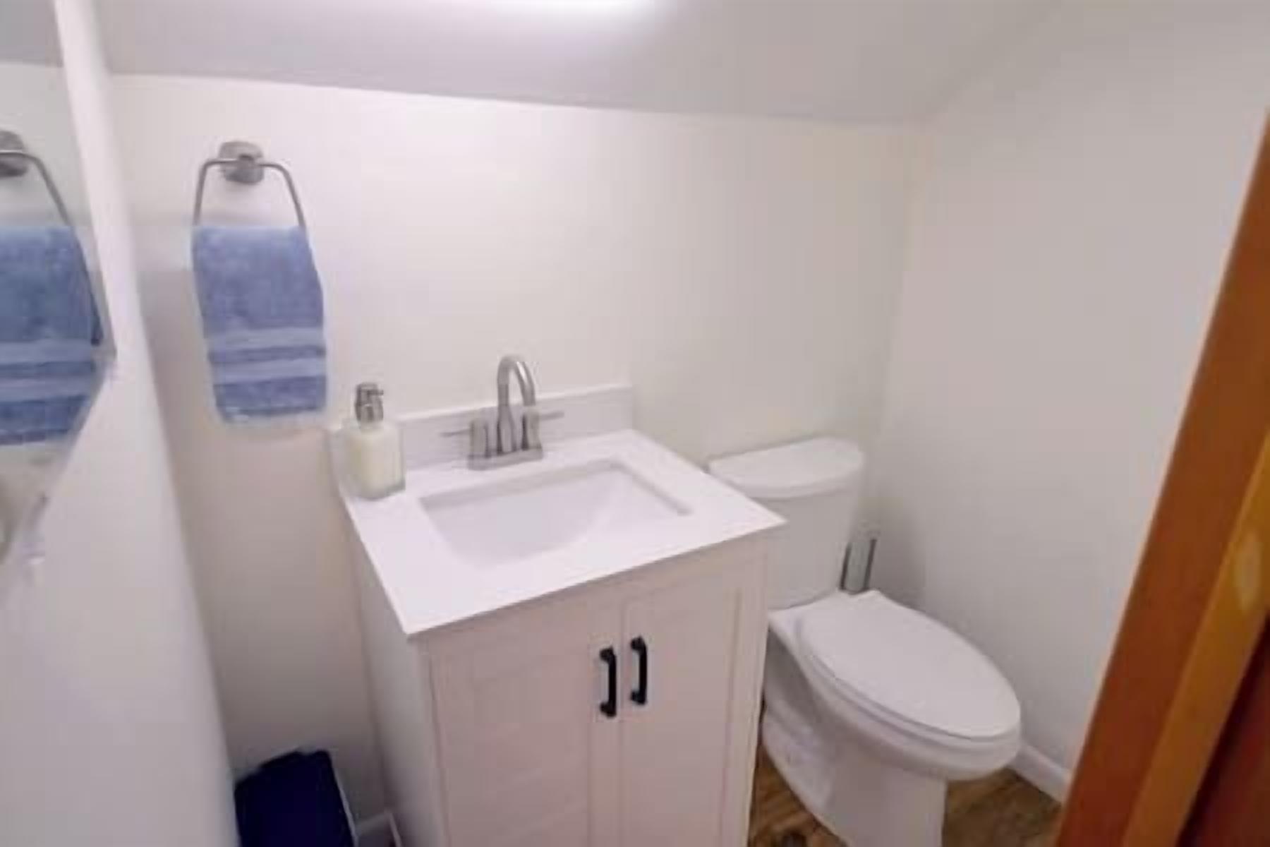 Une petite salle de bain blanche, avec un lavabo, des toilettes et un petit meuble.
