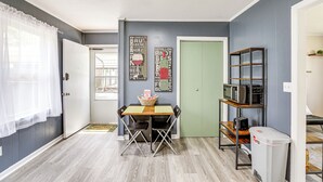 A compact kitchen with a dining table, chairs, a microwave shelf, and a trash bin. - < 5 Mi to Dtwn Walterboro: Grill, Game & More! (Walterboro)