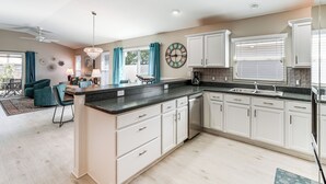 Una cocina moderna con armarios blancos, encimera negra y lavavajillas integrado.