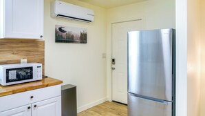 Una cocina compacta con un refrigerador de acero inoxidable, un microondas y un mueble pequeño.