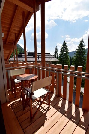 Une terrasse en bois avec une table et des chaises, offrant une vue sur un paysage montagneux.