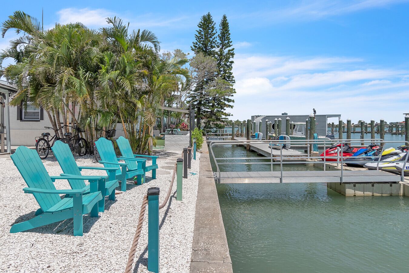 Un port de plaisance avec des bateaux, un quai et une rangée de chaises turquoise.