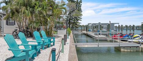 Un port de plaisance avec des bateaux, un quai et une rangée de chaises turquoise.
