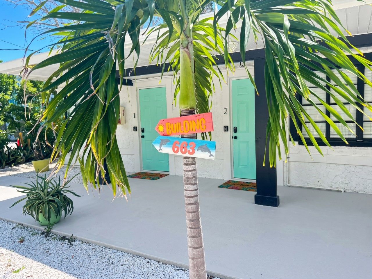 A building with teal doors, a palm tree, and a sign indicating a building number 683.
