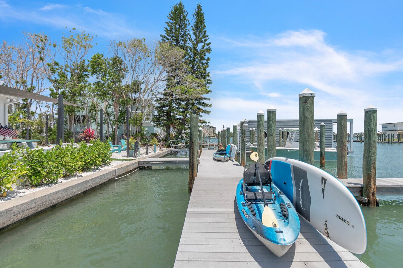 A marina with a dock, kayaks, and a paddleboard.
