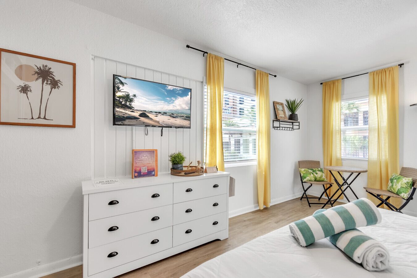 A bedroom with a bed, a dresser, a TV, and two chairs.