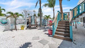 A beachfront property with a sign indicating vacation rentals, jet skis, parasails, golf carts, and island & fishing charters. - Stylish Waterside Studio 2 blocks to Beach (Clearwater Beach)