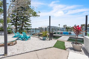 A waterfront patio with outdoor seating, a pool, and a boat dock.