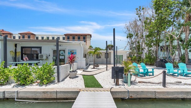 Una propiedad frente al agua con muelle, asientos exteriores y un edificio con un letrero que dice 'Office'.