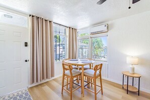Une pièce comprenant une table à manger, des chaises, une petite table d’appoint et une fenêtre avec des rideaux.