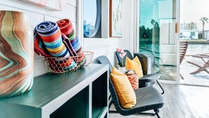 A modern interior with a seating area by a glass door, a colorful striped rug, and a wicker chair with cushions.
