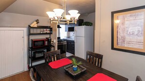 Una cocina compacta con una mesa de comedor, sillas, un refrigerador, un microondas y una estufa.