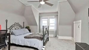Un dormitorio con cama, ventilador de techo, ventana y puerta.