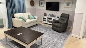 Een woonkamer met een bank, een salontafel, een televisie en een fauteuil.
