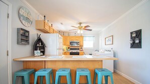 A kitchen with a central island, wooden cabinets, a microwave, and a ceiling fan.