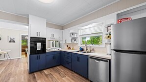 A modern kitchen with a stainless steel refrigerator, a black oven, and a dishwasher.