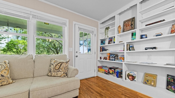 A room with a beige sofa, a white bookshelf, and a door with a window.