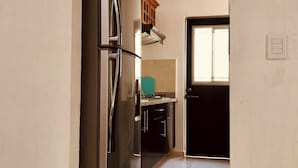 Una cucina con frigorifero in acciaio inox, mobili in legno e pavimento piastrellato.
