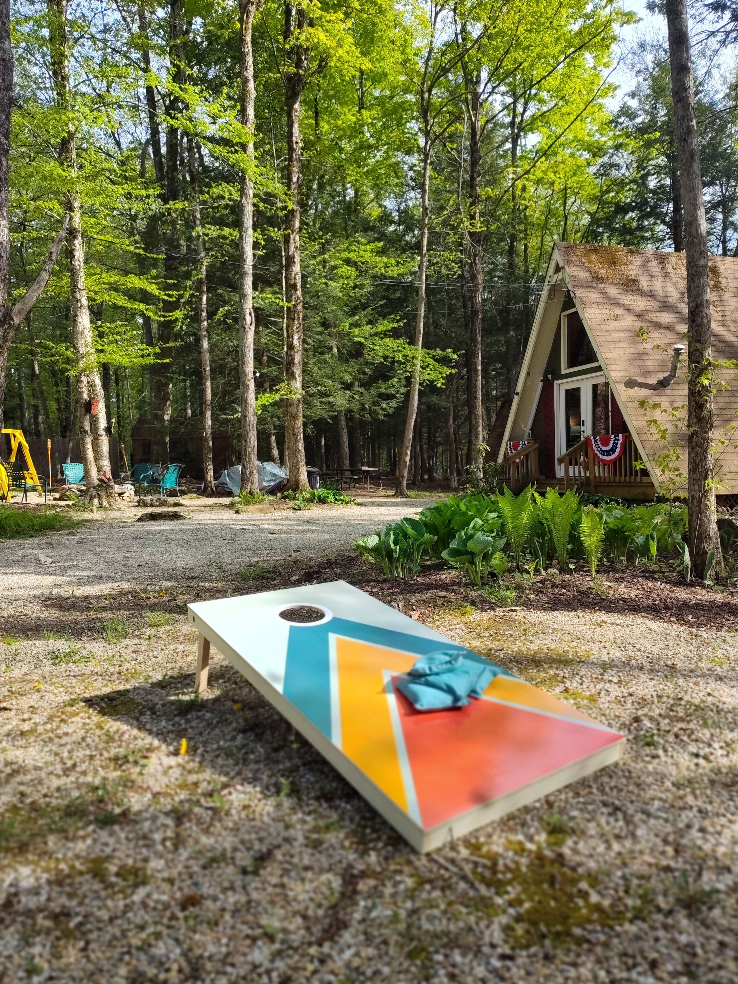 Ein bewaldetes Gebiet mit einer kleinen Holzhütte und einem bunten Gesellschaftsspiel im Vordergrund.