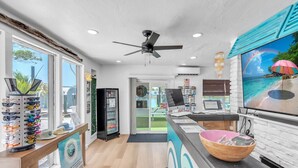 A reception area with a counter, computer, and a large TV displaying a beach scene. - Direct Waterfront `The Lily Pad` Walk to Beach (Clearwater Beach)