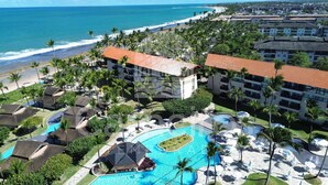 A resort with a large pool, palm trees, and a beach view. - Marulhos Suítes Resort (Ipojuca)