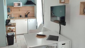 A modern kitchen with white cabinets, a microwave, and a hanging plant.