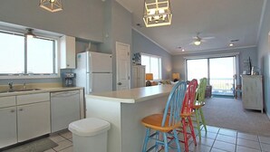 Una cocina amplia con una isla central, armarios blancos y sillas coloridas.