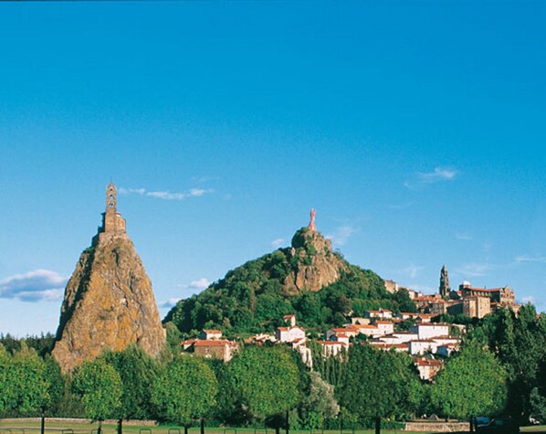 A town with a prominent rock formation and a church on a hill.