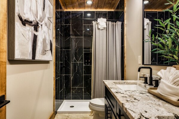 Une salle de bain avec douche, toilettes et lavabo.