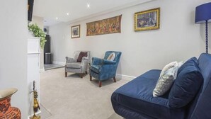 A living room with a blue sofa, two armchairs, a white armchair, and a decorative vase.