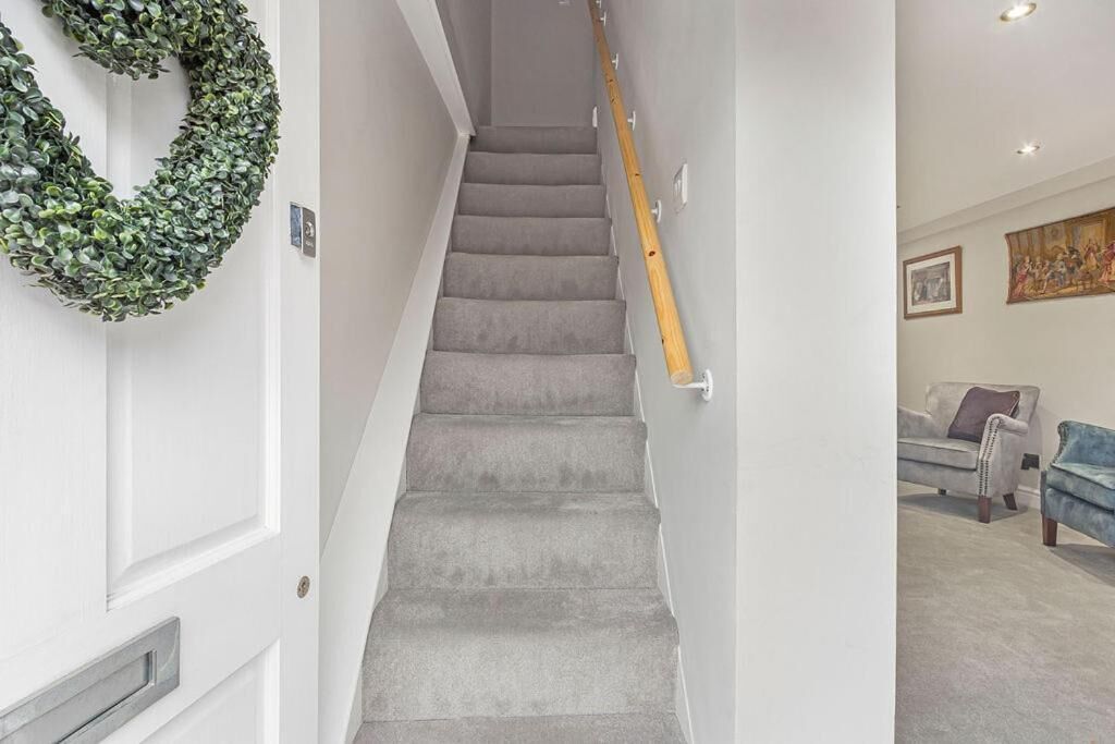 A staircase with grey carpeted steps, a wooden handrail, and a green wreath on the wall.