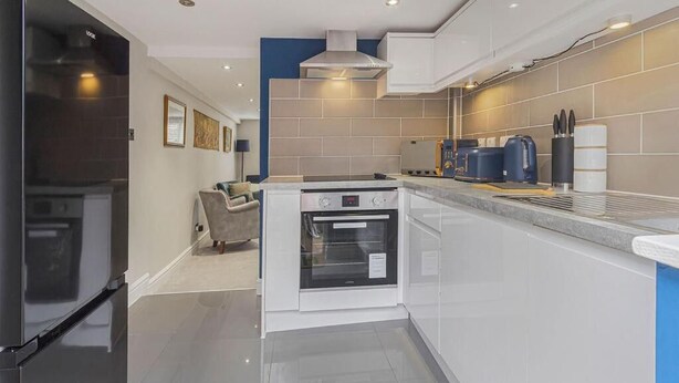 A modern kitchen with a built-in oven, a coffee machine, and a refrigerator.