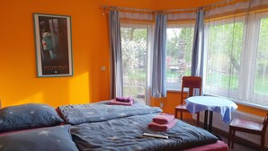 Una camera da letto con un letto, cuscini, una sedia, un tavolo e tende.