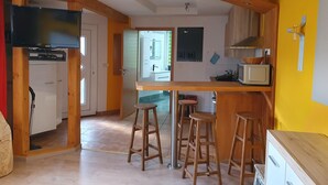 Una cucina compatta con elementi in legno, una zona pranzo con sgabelli e un televisore.