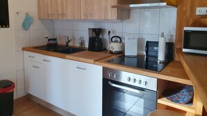 Una cucina moderna con mobili bianchi, un forno in acciaio inossidabile, una macchina da caffè e un forno a microonde.