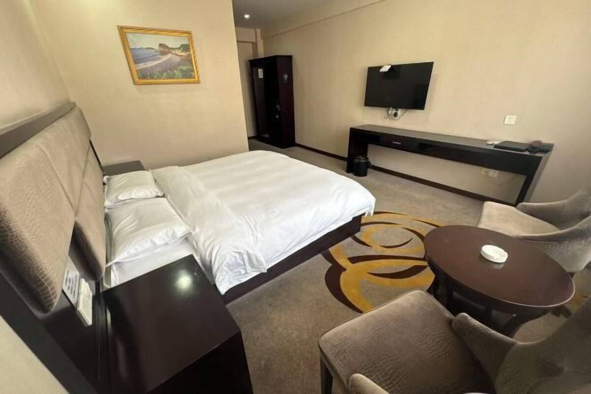 A hotel room with a bed, a desk, a TV, a chair, and a small table.