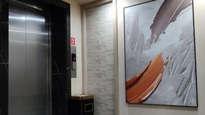 Un ascensor con detalles de mármol, una pared de ladrillo y un cuadro abstracto de gran tamaño en la pared.
