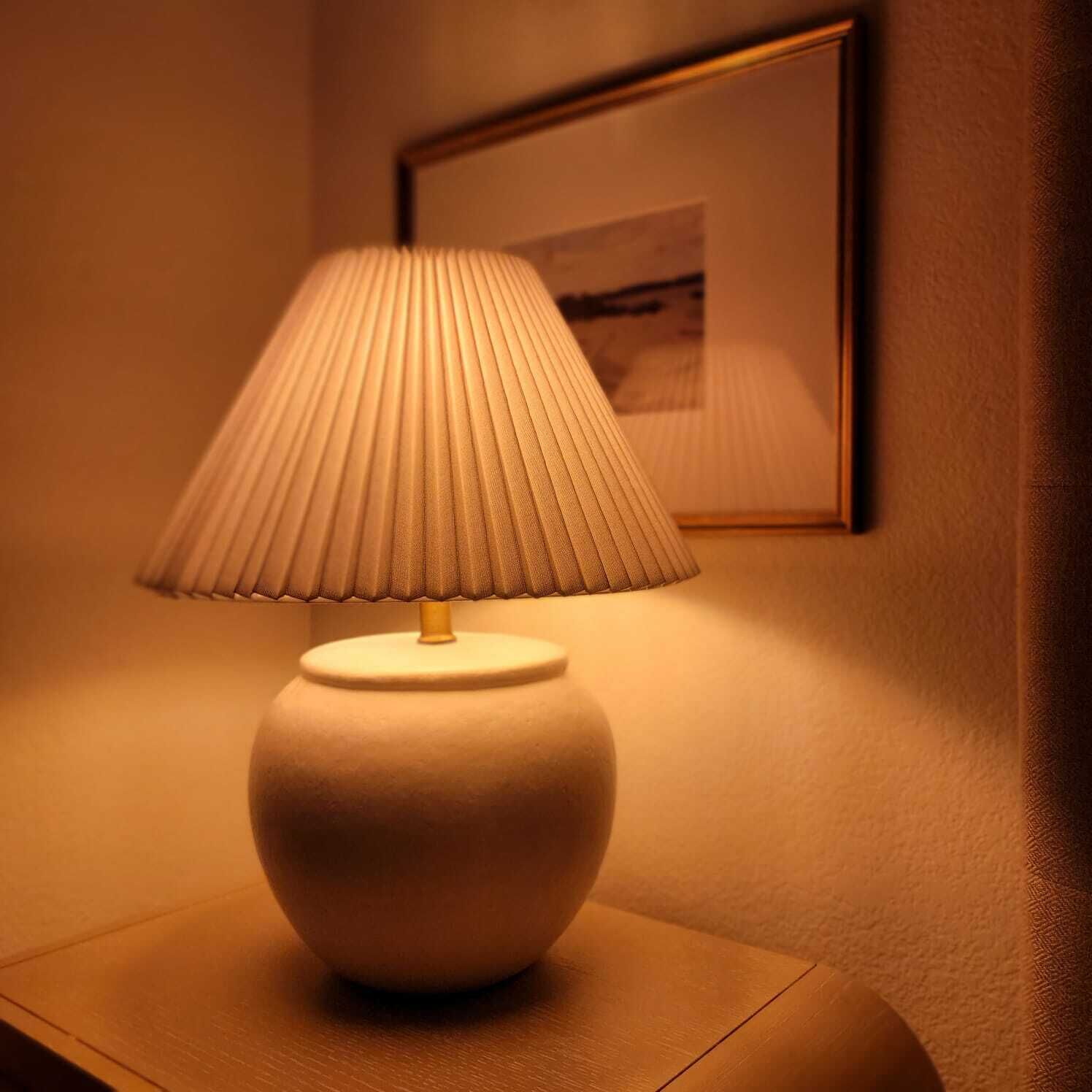 A table lamp with a ribbed lampshade on a bedside table.