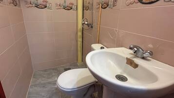 Un bagno con il water, lavandino e doccia.