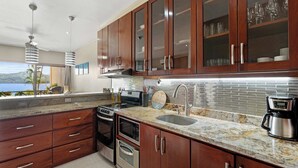 A modern kitchen with wooden cabinets, a stainless steel sink, and a view of the outdoors. - Ground-Floor Condo Near Beach & Marina by SPCR (Playa Flamingo)