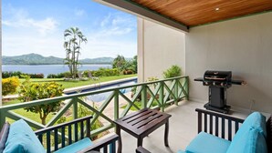 A balcony with a view of a lake and mountains, a barbecue grill, and outdoor seating. - Ground-Floor Condo Near Beach & Marina by SPCR (Playa Flamingo)