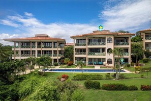 A multi-story hotel with a swimming pool and lush landscaping. - Ground-Floor Condo Near Beach & Marina by SPCR (Playa Flamingo)