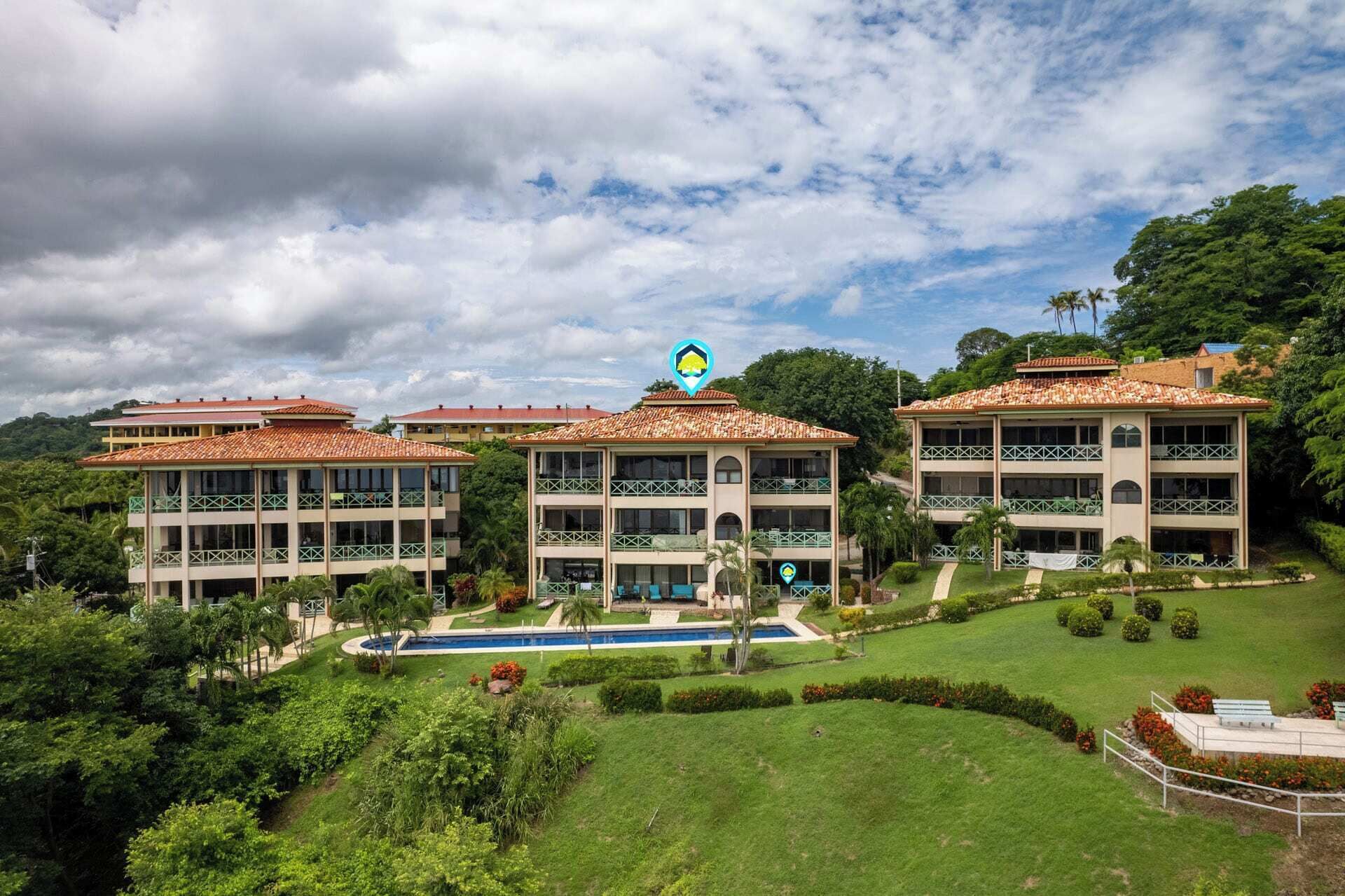 Un hotel con varias edificaciones, piscina y abundante vegetación.