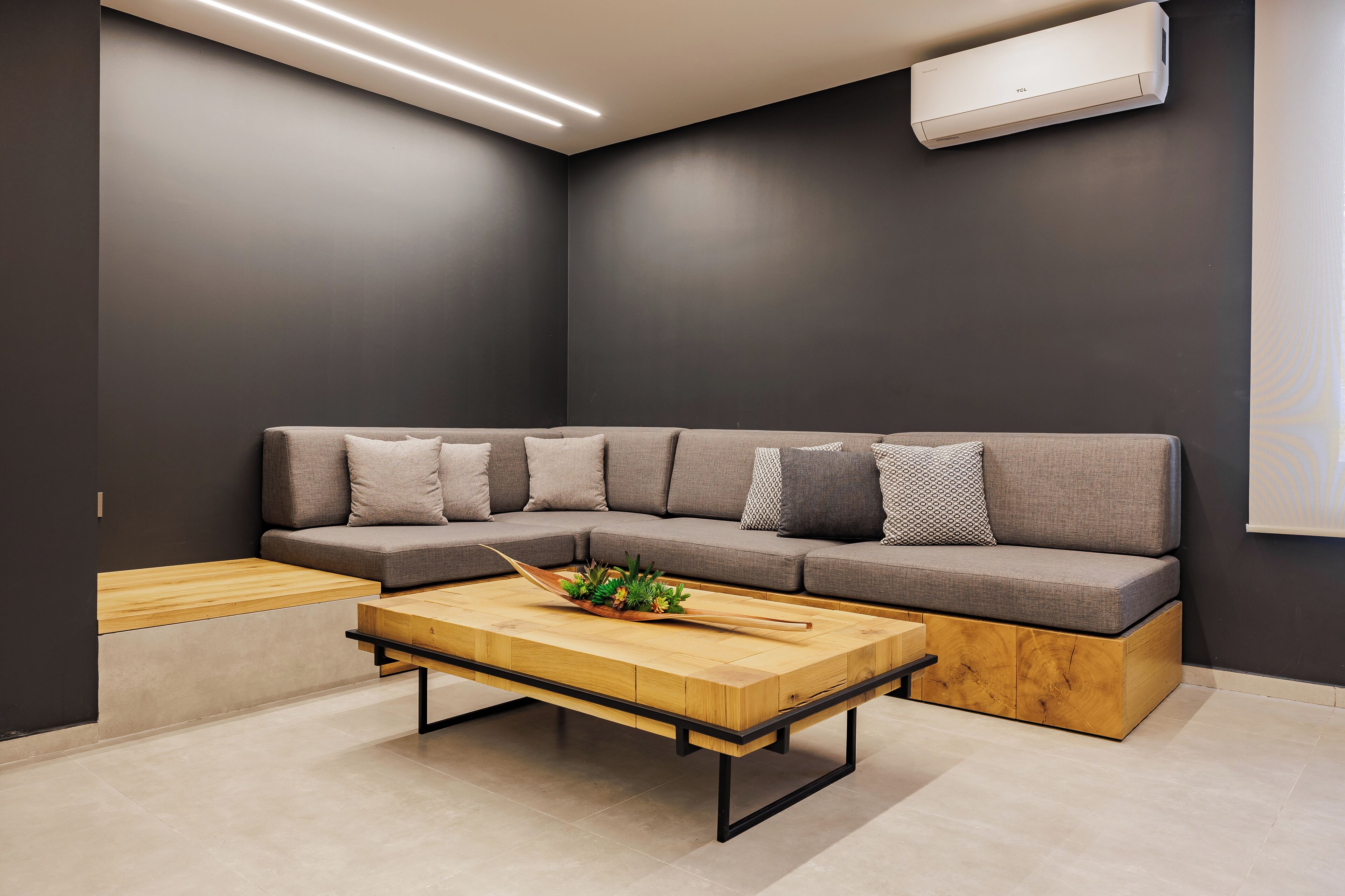 A modern living room with a sectional sofa, a wooden coffee table, and a built-in bench.