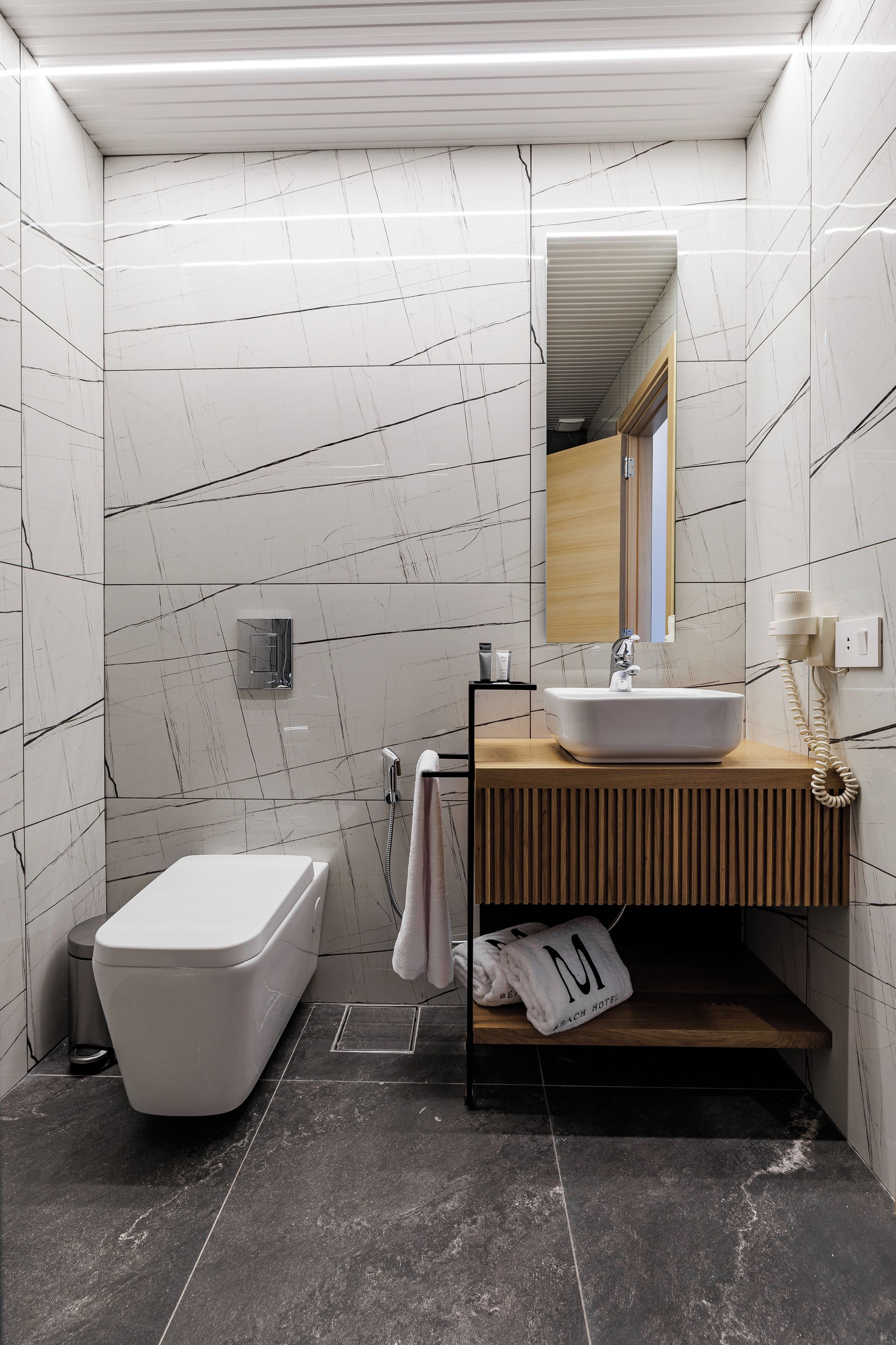 A bathroom with a white bathtub, a wooden vanity with a sink, a mirror, and a towel rack.