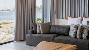 Una sala de estar moderna con un ventanal grande, cortinas grises, un sofá gris con cojines estampados y una mesa de centro de madera.