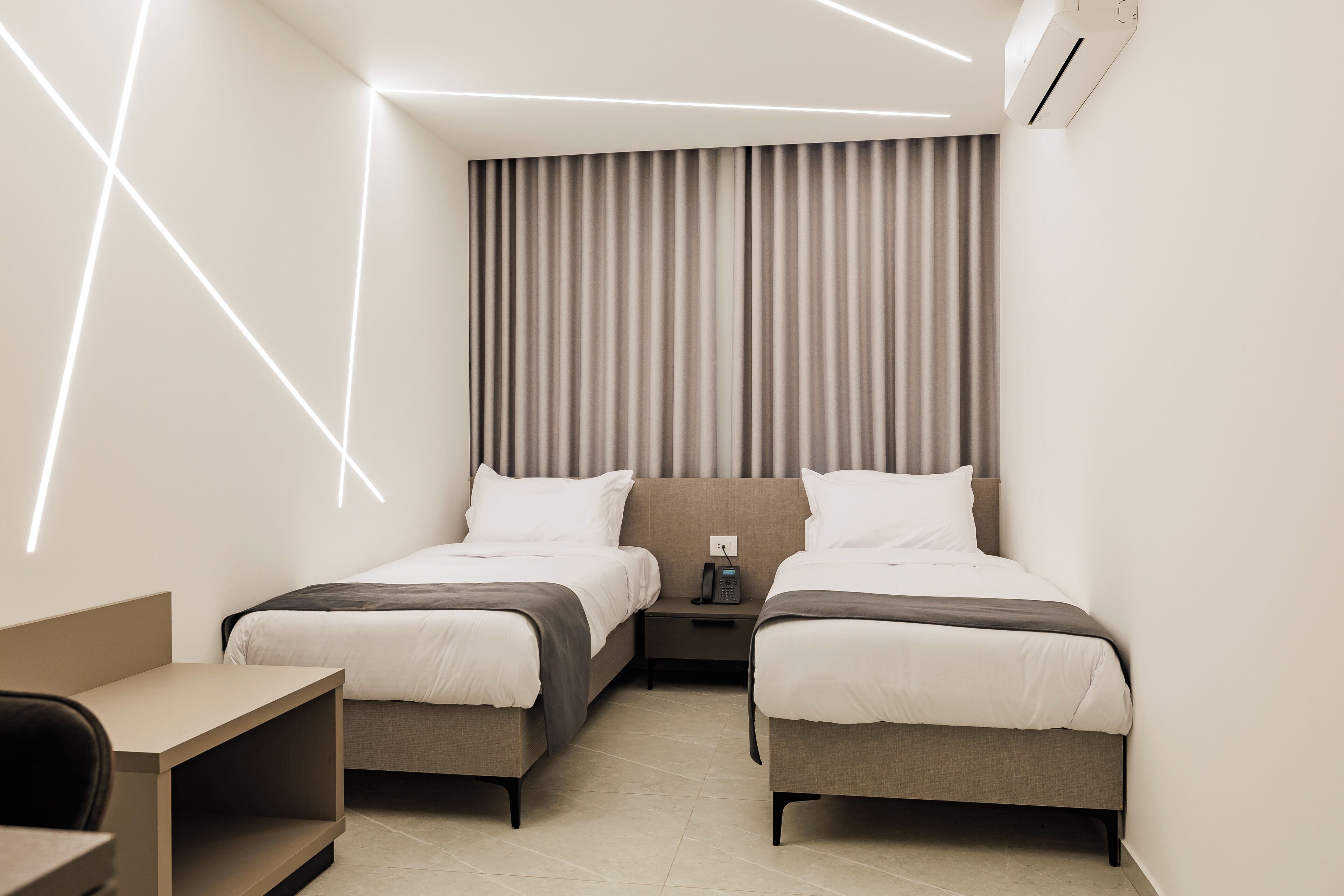 Une chambre d’hôtel moderne avec deux lits, un bureau et une table de chevet.