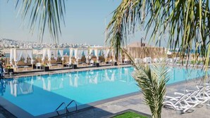 Una piscina con sillones de descanso y vistas de la ciudad.