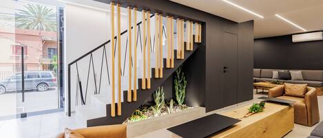 A modern living room with a sofa, a coffee table, and a staircase with wooden railings.
