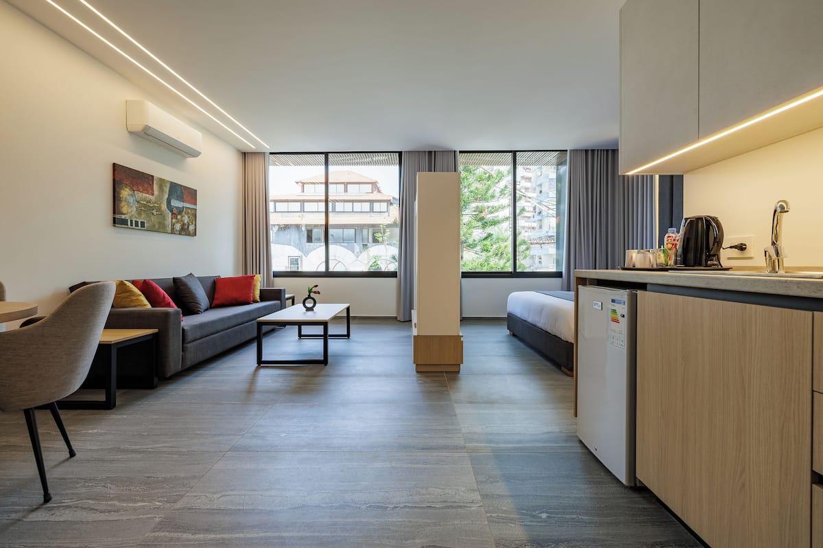 A modern living room with a sofa, dining table, and kitchen area.